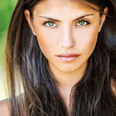 Eine schöne Frau mit braunen langen Haaren und grünen Augen schaut in die Kamera